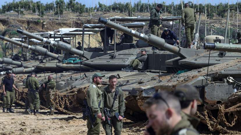 Israeli soldiers stand next to tanks near the Israeli side of the border with Lebanon in northern Israel