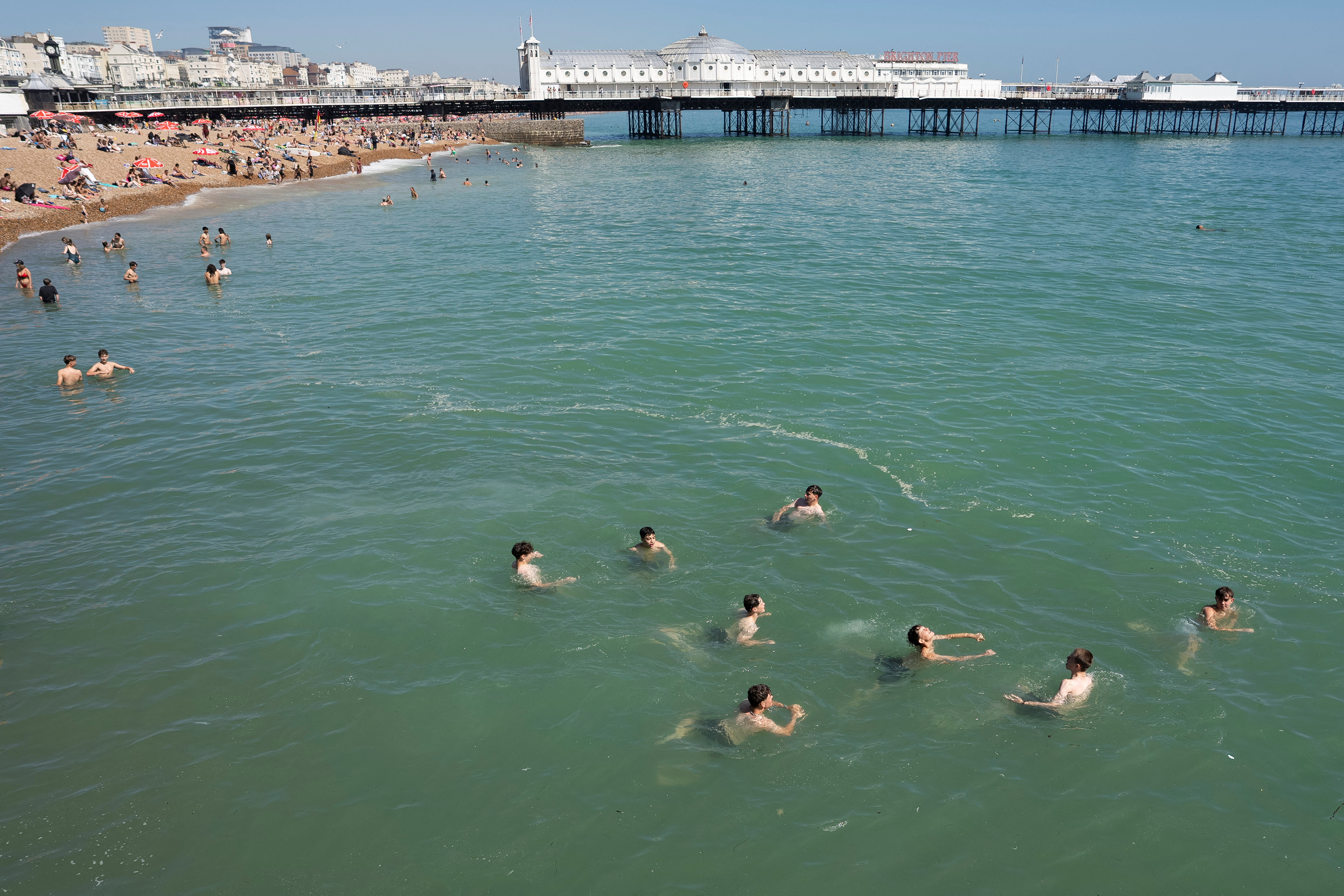 Beachgoers swim in the sea during warm weather as temperatures rise across the UK, in Brighton