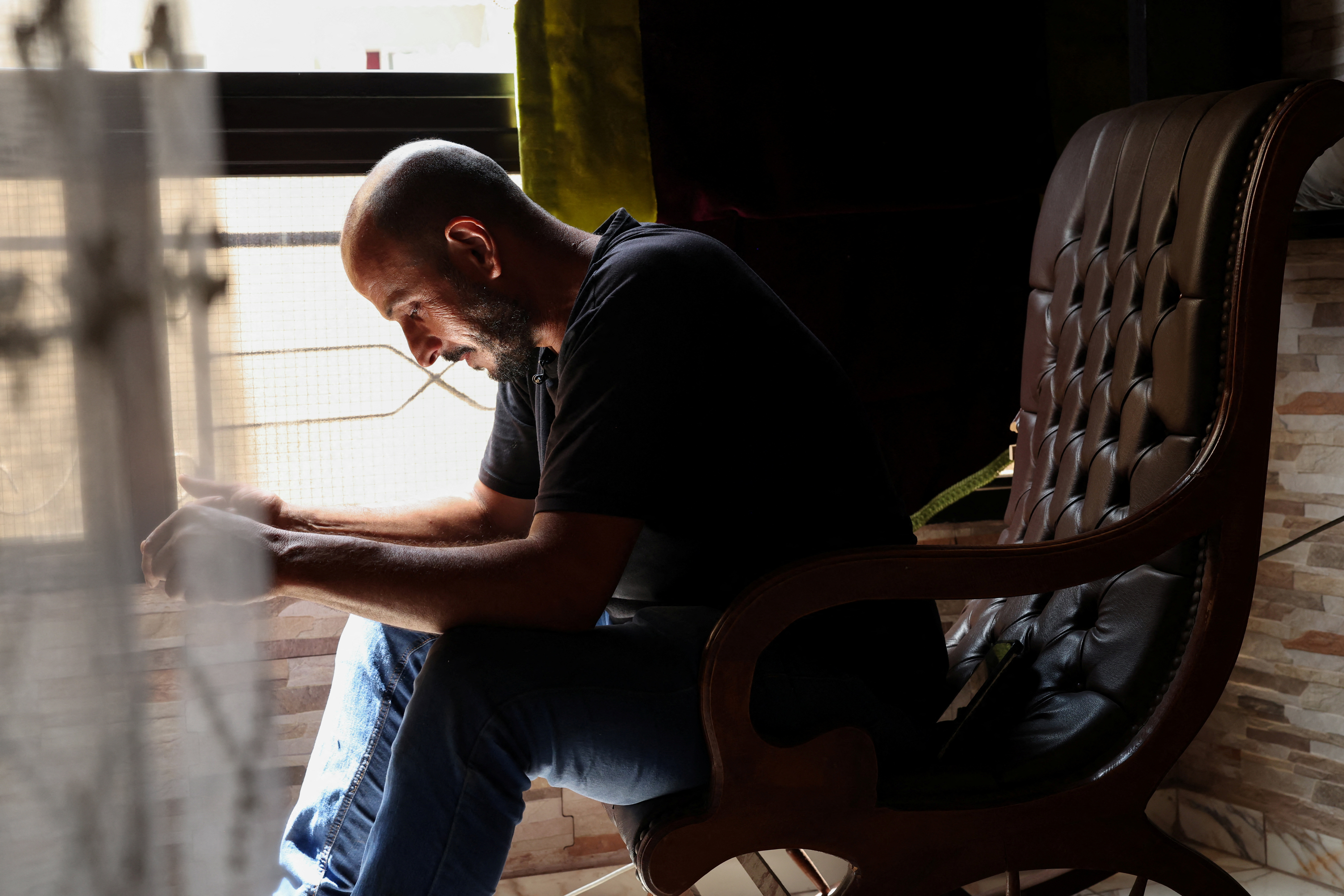 Bilal Sahlab, 45, sits by his window in his home in Dahiyeh