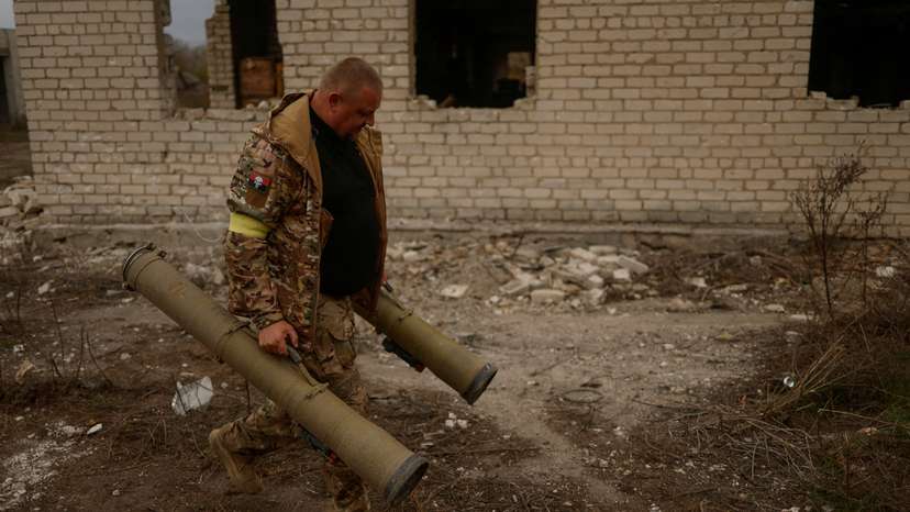 Ukrainian serviceman carries captured anti-tank grenade launchers at a former position of Russian soldiers in the village of Blahodatne in Kherson region