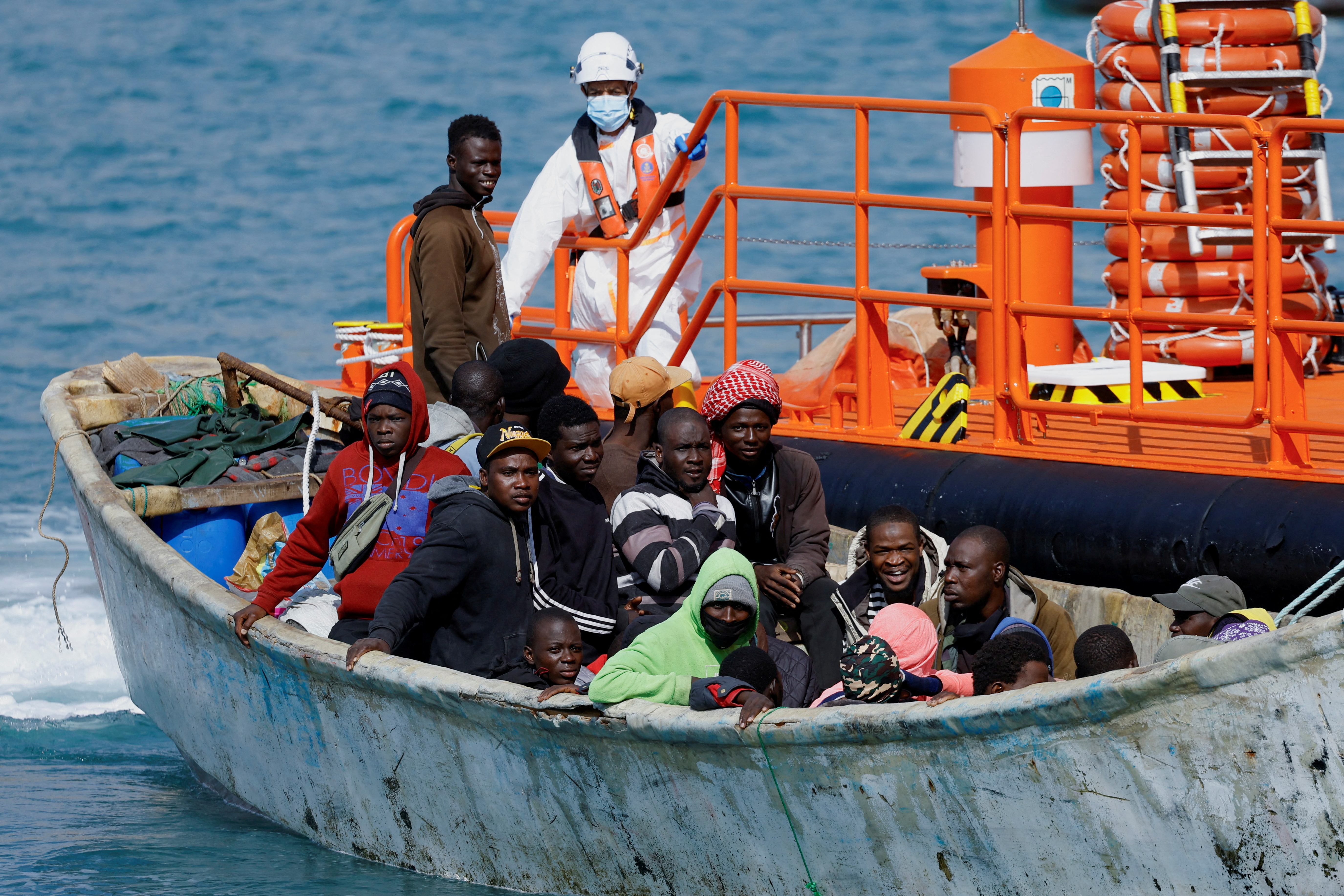FILE PHOTO: A group of migrants wait to disembark from a wooden boat after being rescued by a Spanish coast guard vessel in the port of Arguineguin