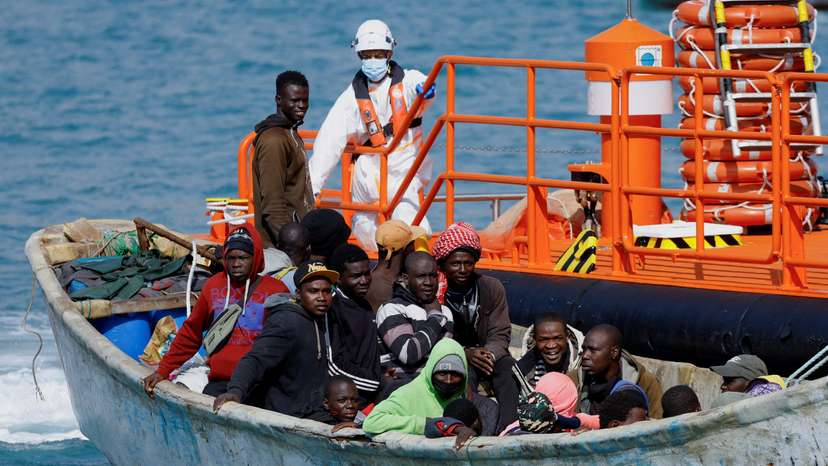 FILE PHOTO: A group of migrants wait to disembark from a wooden boat after being rescued by a Spanish coast guard vessel in the port of Arguineguin