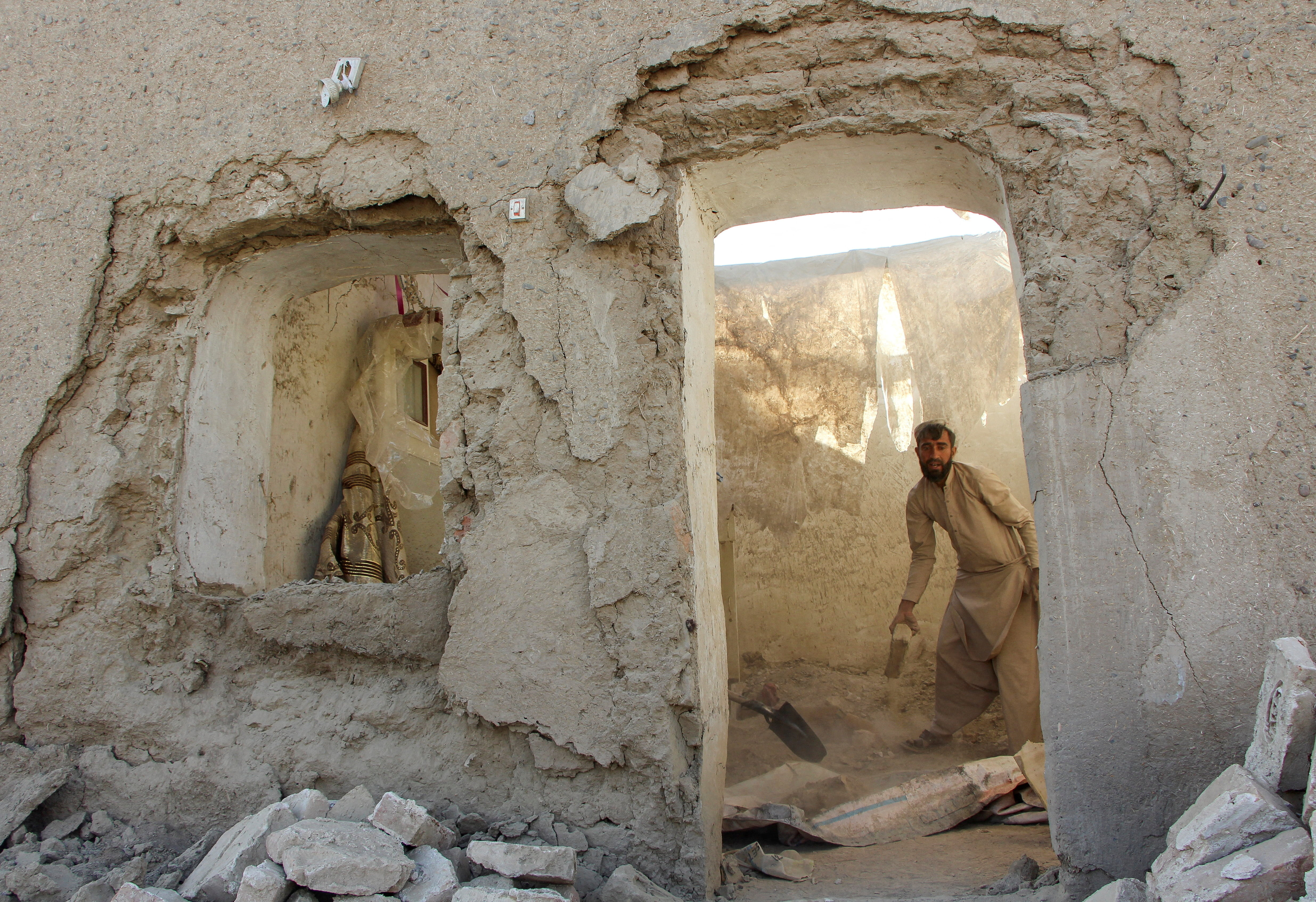 A man clears debris from his house damaged during an airstrike following a temporary ceasefire amid the conflict between Afghanistan and Pakistan, in Spin Boldak