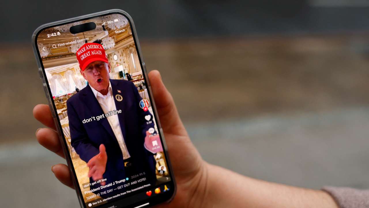 A woman poses with her smartphone displaying the @realdonaldtrump TikTok page, in Washington
