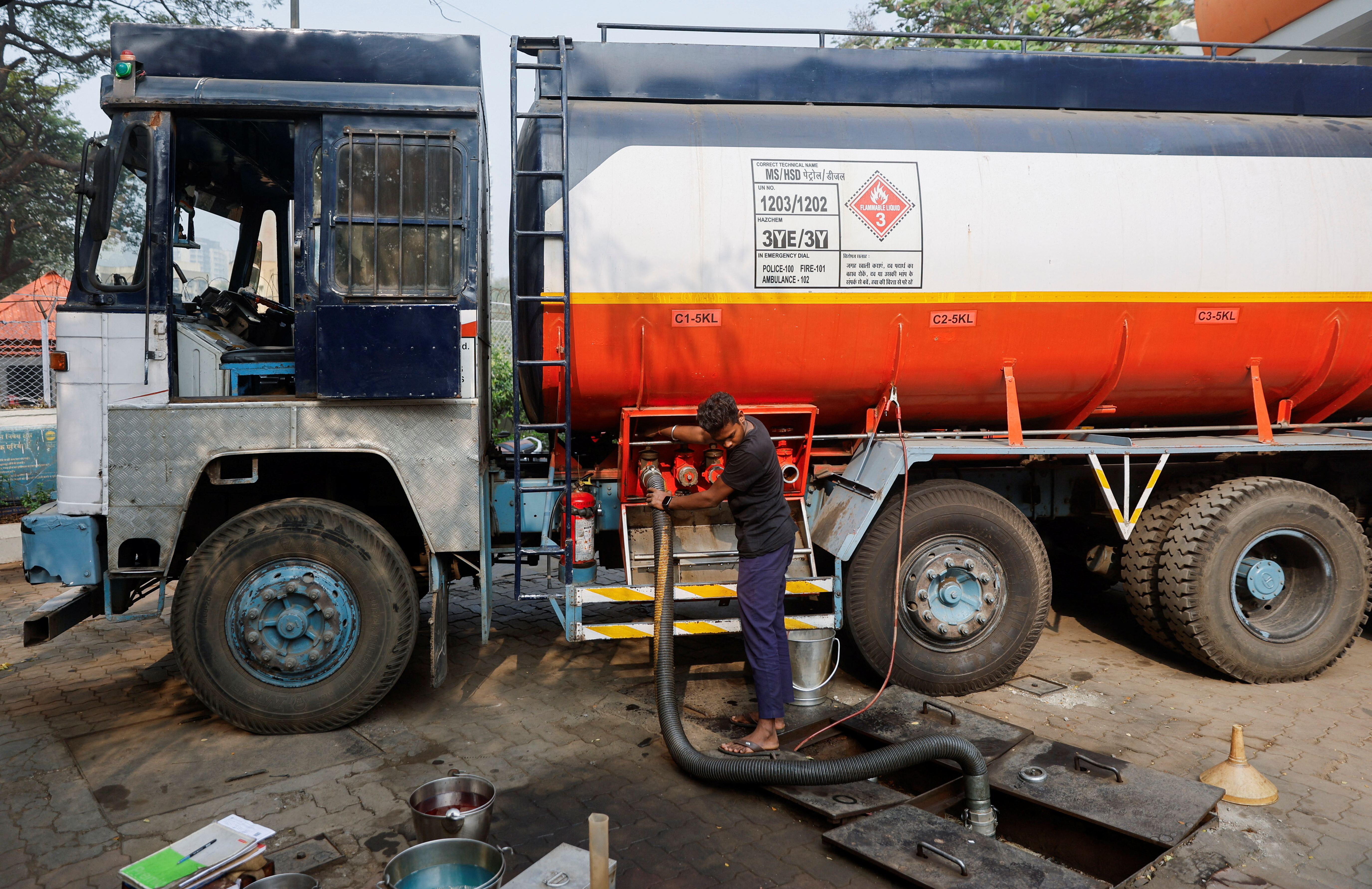 A man opens a valve of a fuel tanker during the refilling of an underground fuel tank, after a petrol pump ran out of fuel after shortages in Mumbai
