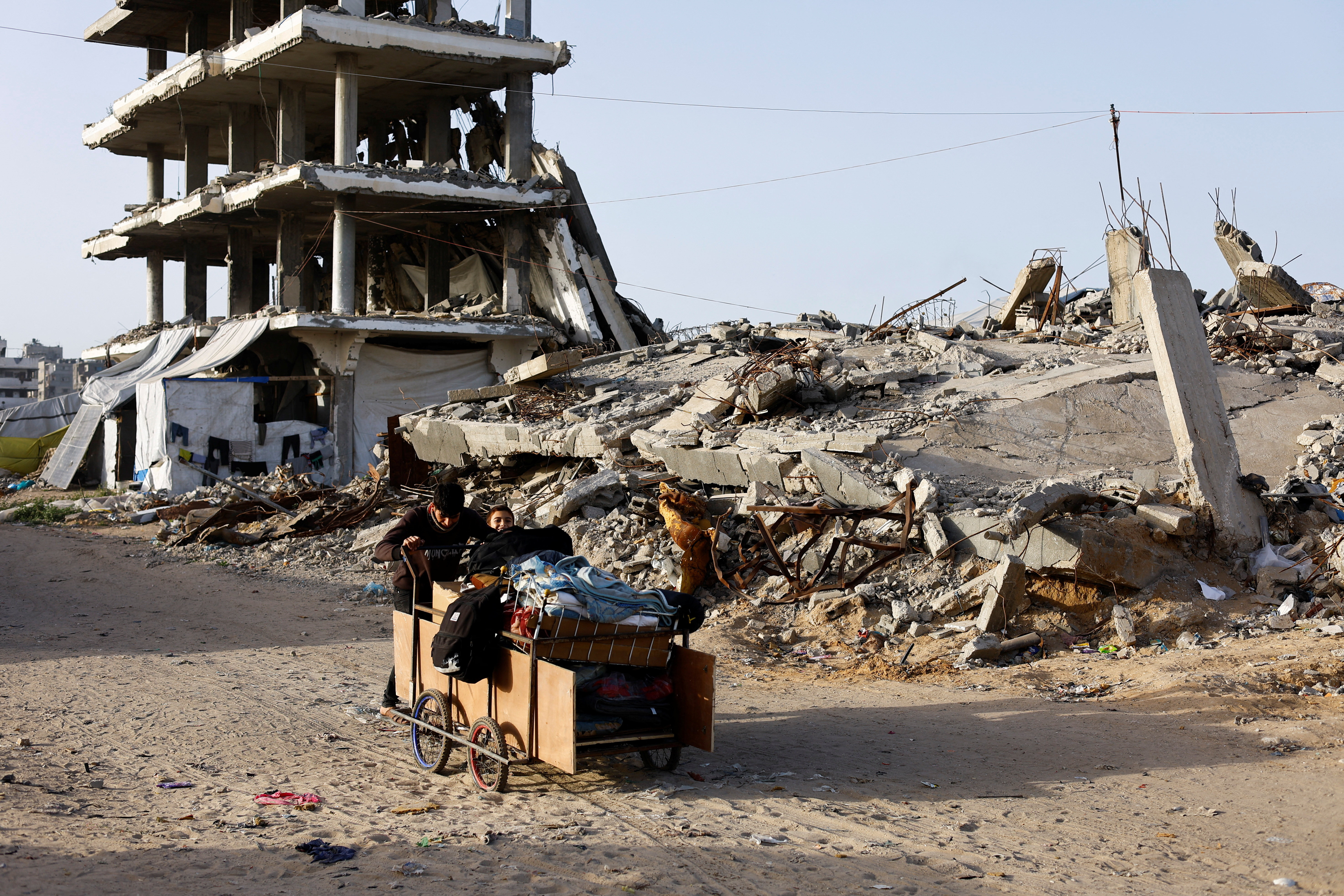 Palestinians push a cart past the rubble of residential buildings destroyed during the two-year Israeli offensives, in Gaza City