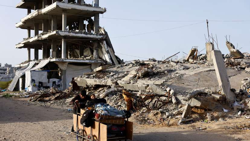 Palestinians push a cart past the rubble of residential buildings destroyed during the two-year Israeli offensives, in Gaza City