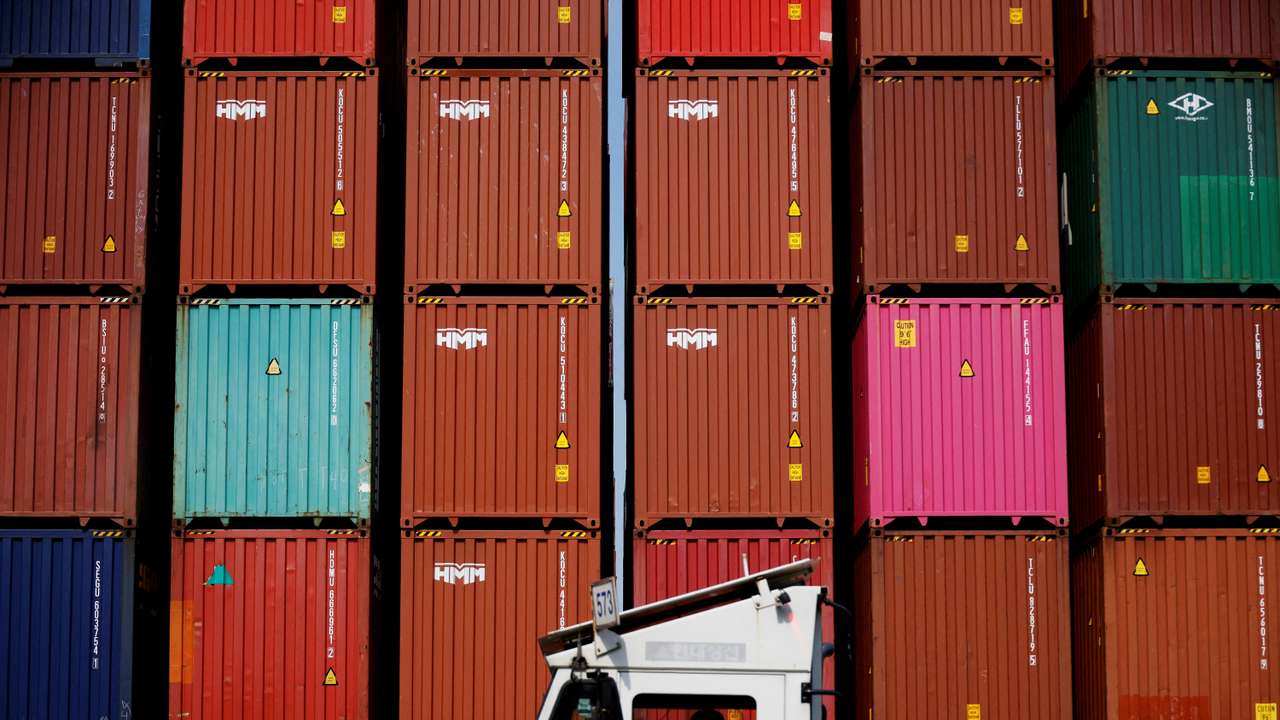 FILE PHOTO: FILE PHOTO: A truck driver works in front of shipping containers stacked up at Pusan Newport Terminal in Busan