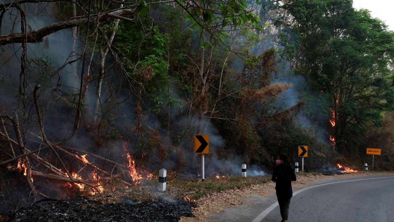 FILE PHOTO: A journalist wears mask near a forest fire in Samoeng District