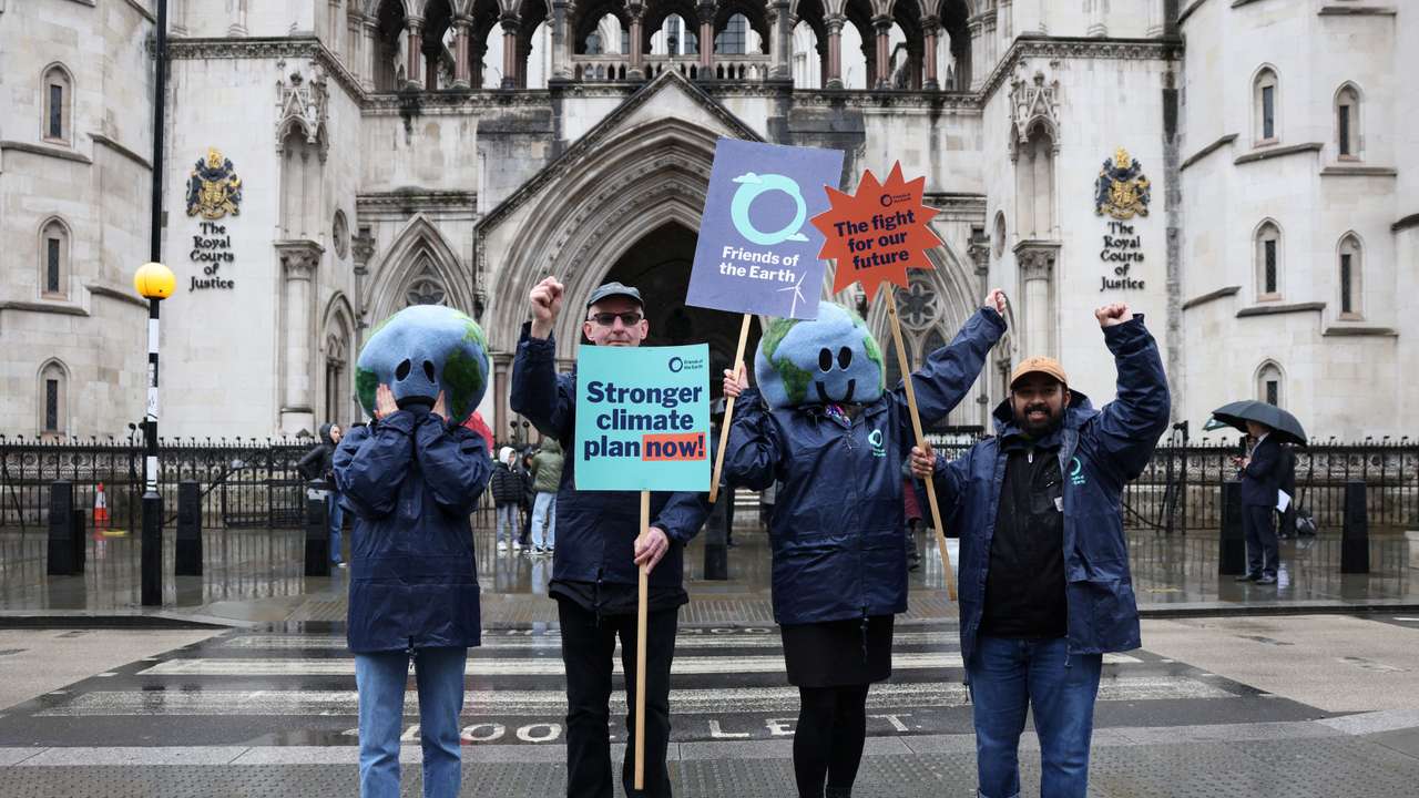 Environmental campaigners hold placards outside the High Court in London