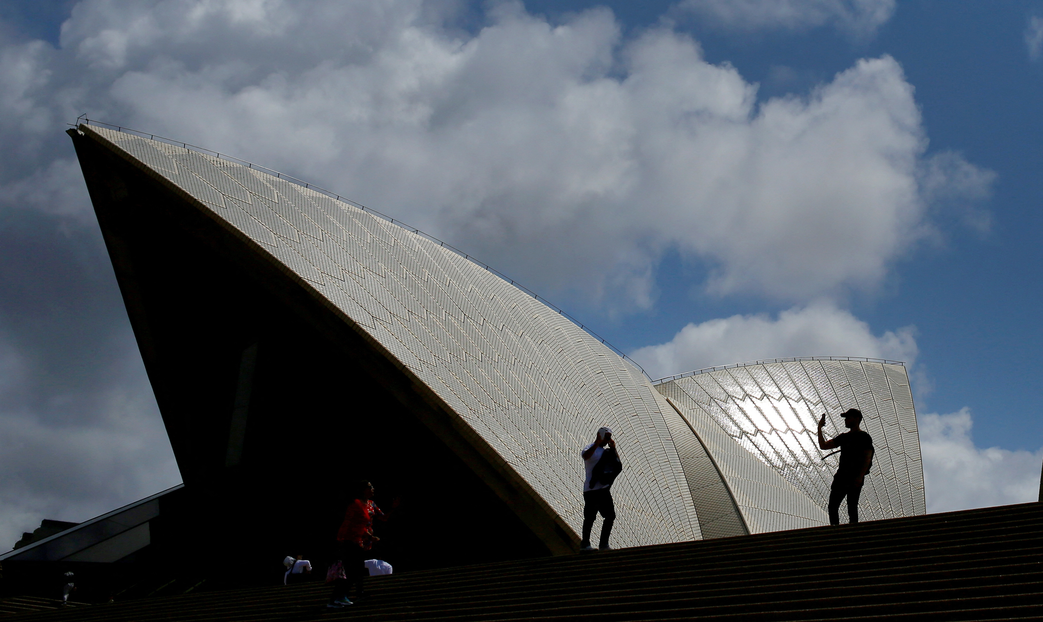 FILE PHOTO: Tourists take photographs with their mobile phones in front of the Sydney Opera House in Sydney