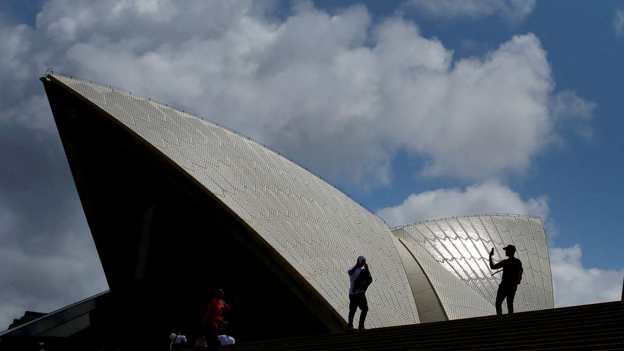 FILE PHOTO: Tourists take photographs with their mobile phones in front of the Sydney Opera House in Sydney