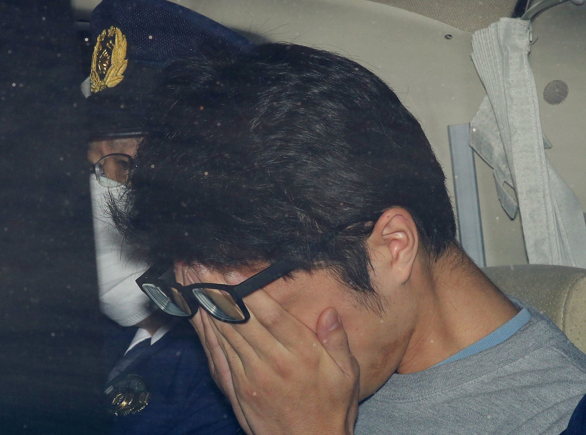 Takahiro Shiraishi covers his face inside a police car in Tokyo