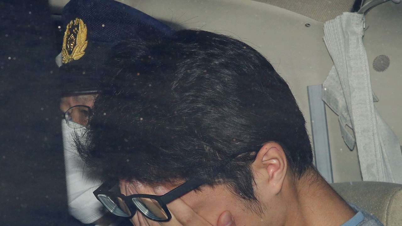 Takahiro Shiraishi covers his face inside a police car in Tokyo