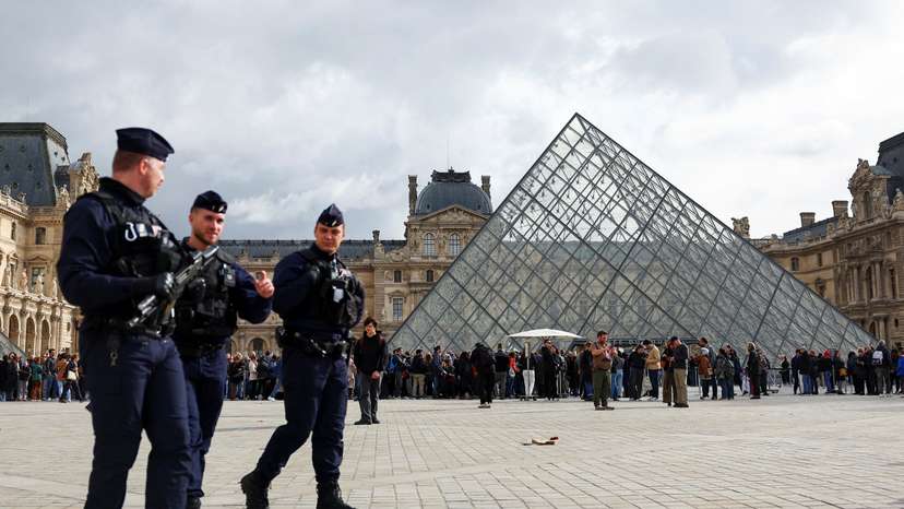 French CRS riot police walk near the glass Pyramid of the Louvre Museum