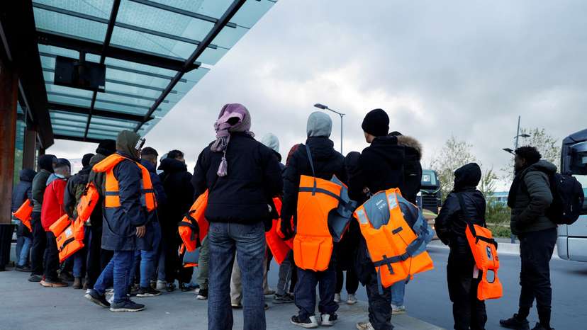 FILE PHOTO: Migrants wait for a bus to return from the beach to their camp, at Calais train station