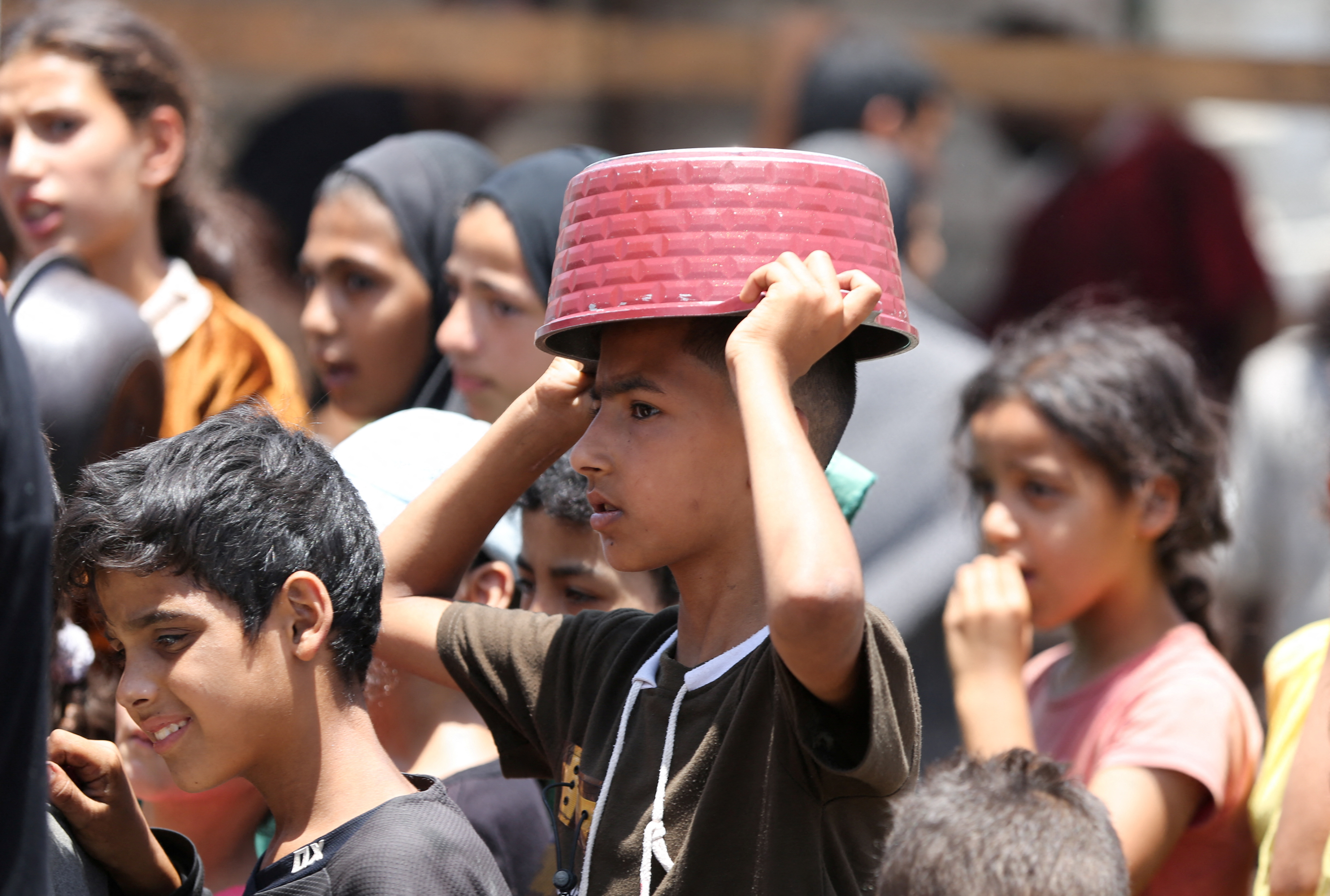 Palestinians gather to receive food cooked by a charity kitchen, in Khan Younis