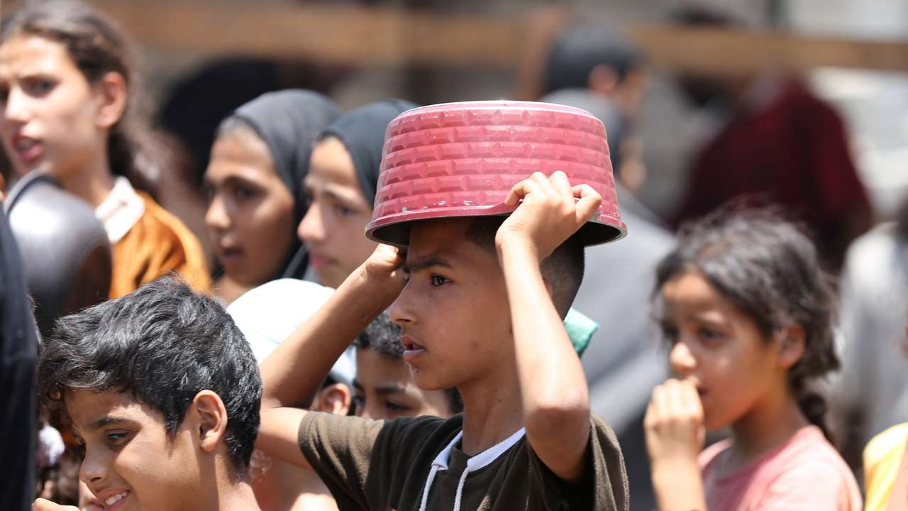 Palestinians gather to receive food cooked by a charity kitchen, in Khan Younis