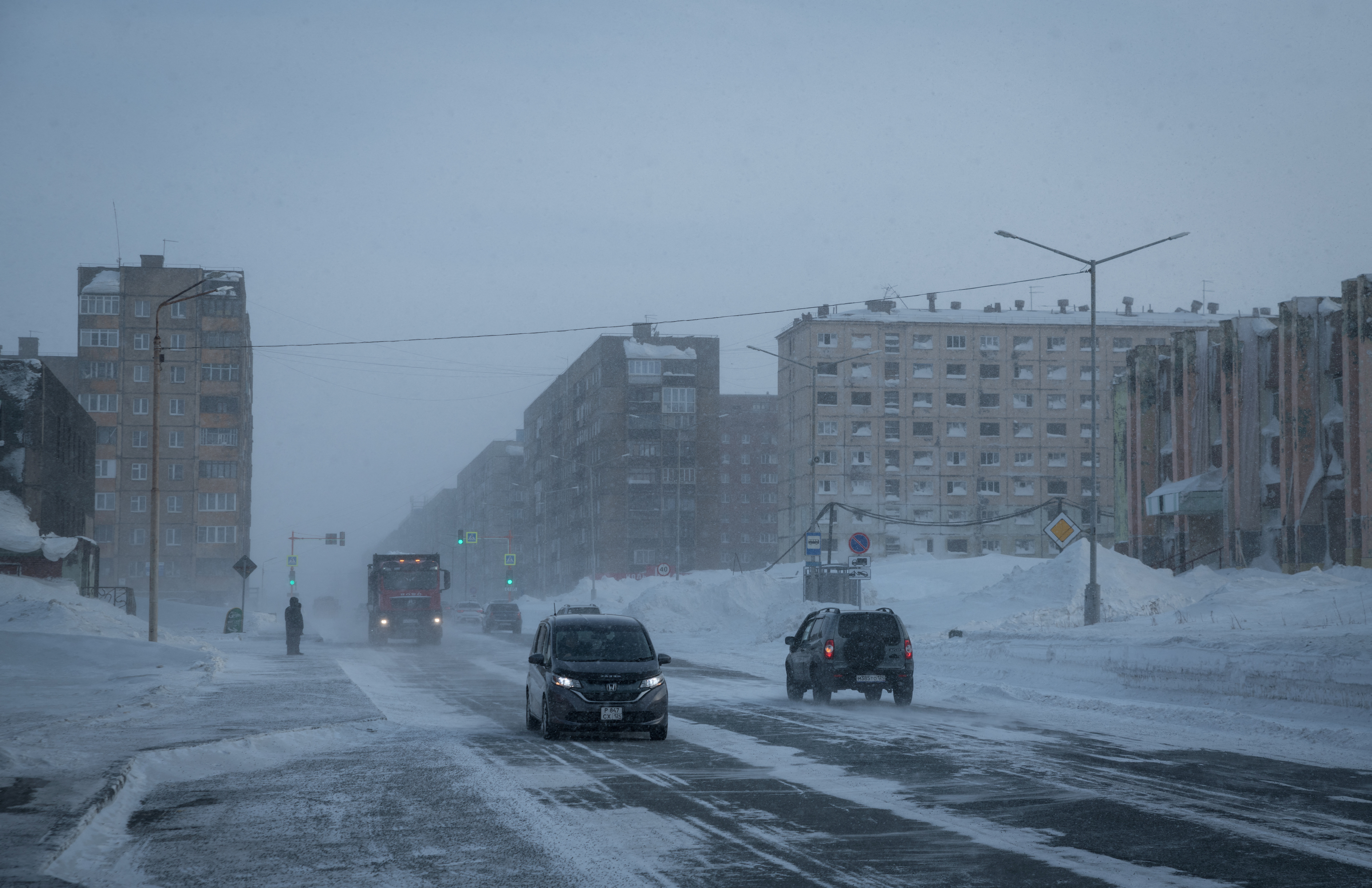 FILE PHOTO: Cars drive along a road during a snowstorm in the Arctic city of Norilsk