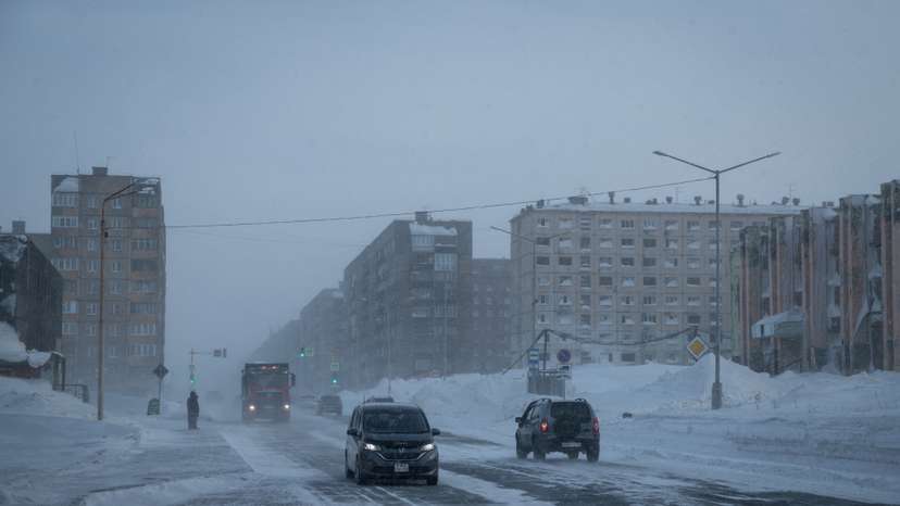 FILE PHOTO: Cars drive along a road during a snowstorm in the Arctic city of Norilsk