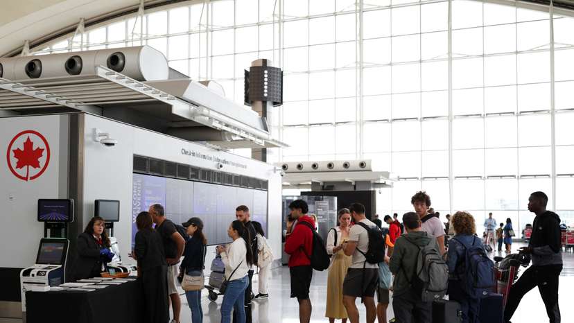 An Air Canada worker stands at a kiosk surrounded by passengers at Toronto Pearson International Airport, following the end of the Air Canada labour strike, in Mississauga