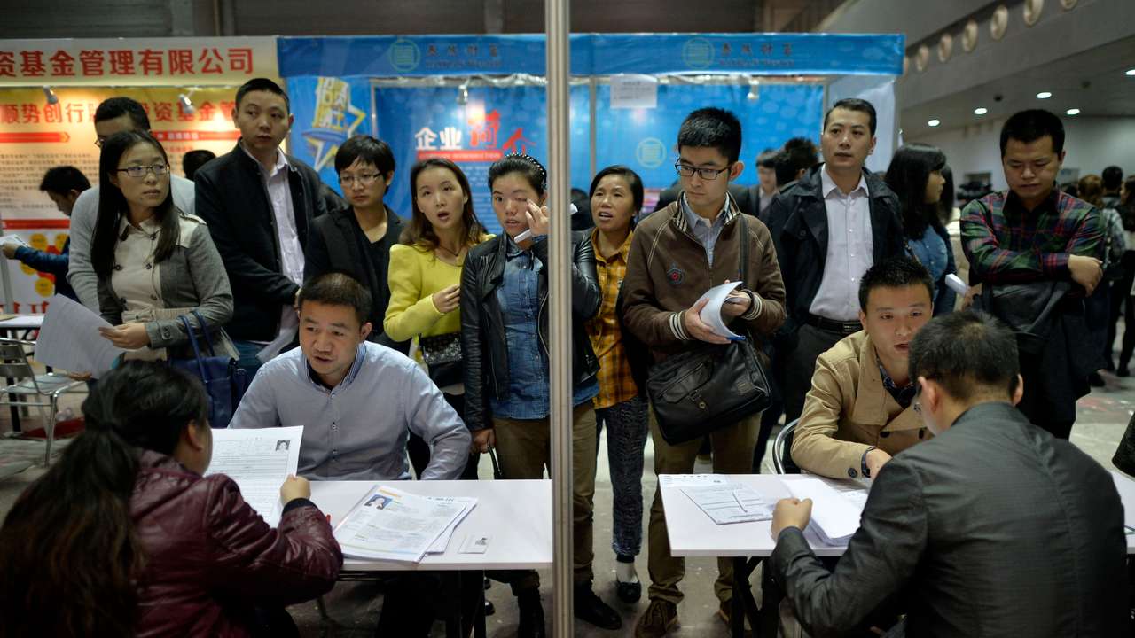 Job seekers speak to recruiters during their interviews at a job fair in Chongqing municipality