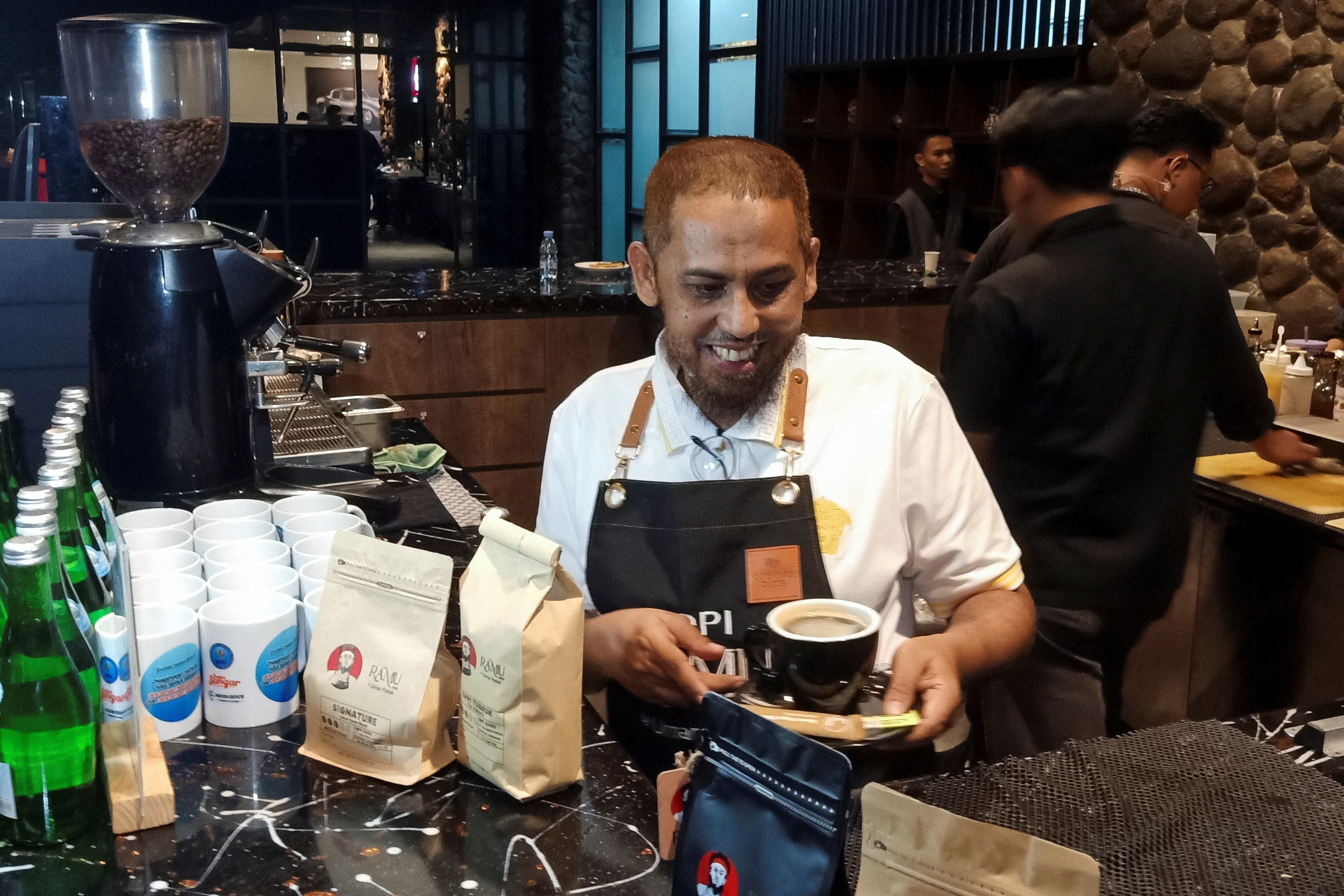 Umar Patek, a 58-year-old former militant who helped assemble the one-tonne bomb that killed 202 people in the 2002 Bali nightclub bombing carries a cup of coffee at a cafe in Surabaya