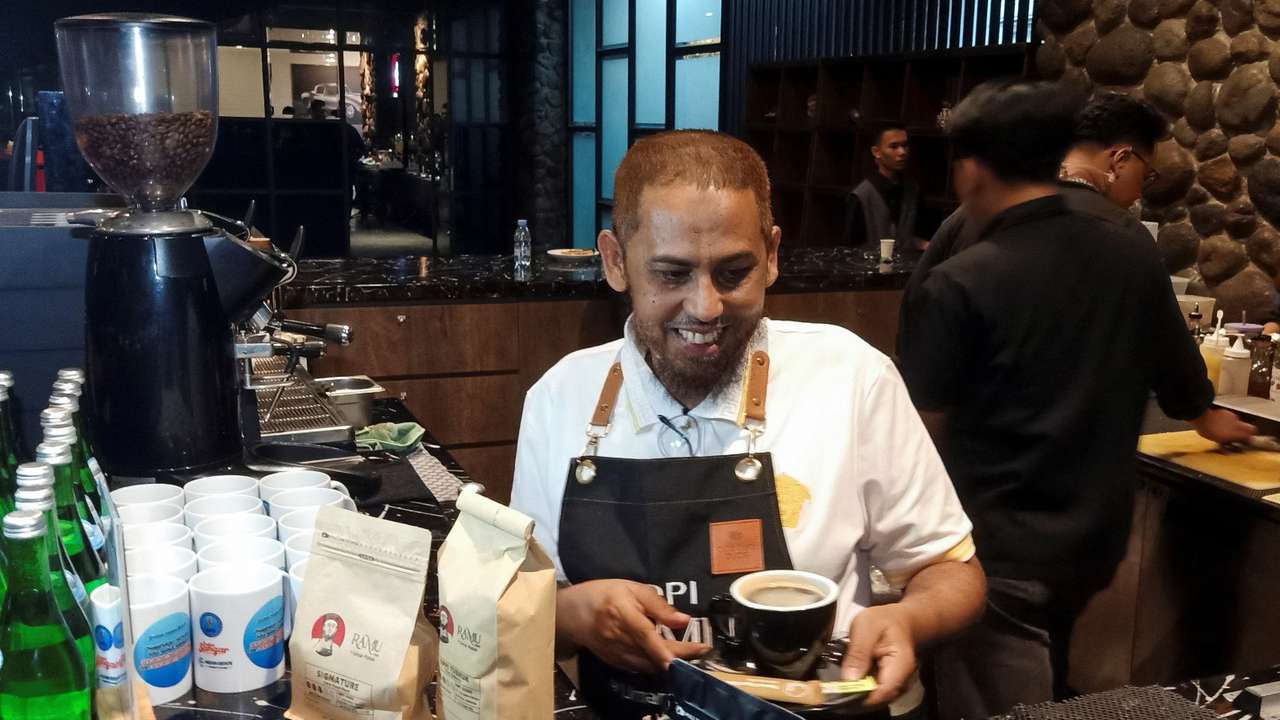 Umar Patek, a 58-year-old former militant who helped assemble the one-tonne bomb that killed 202 people in the 2002 Bali nightclub bombing carries a cup of coffee at a cafe in Surabaya