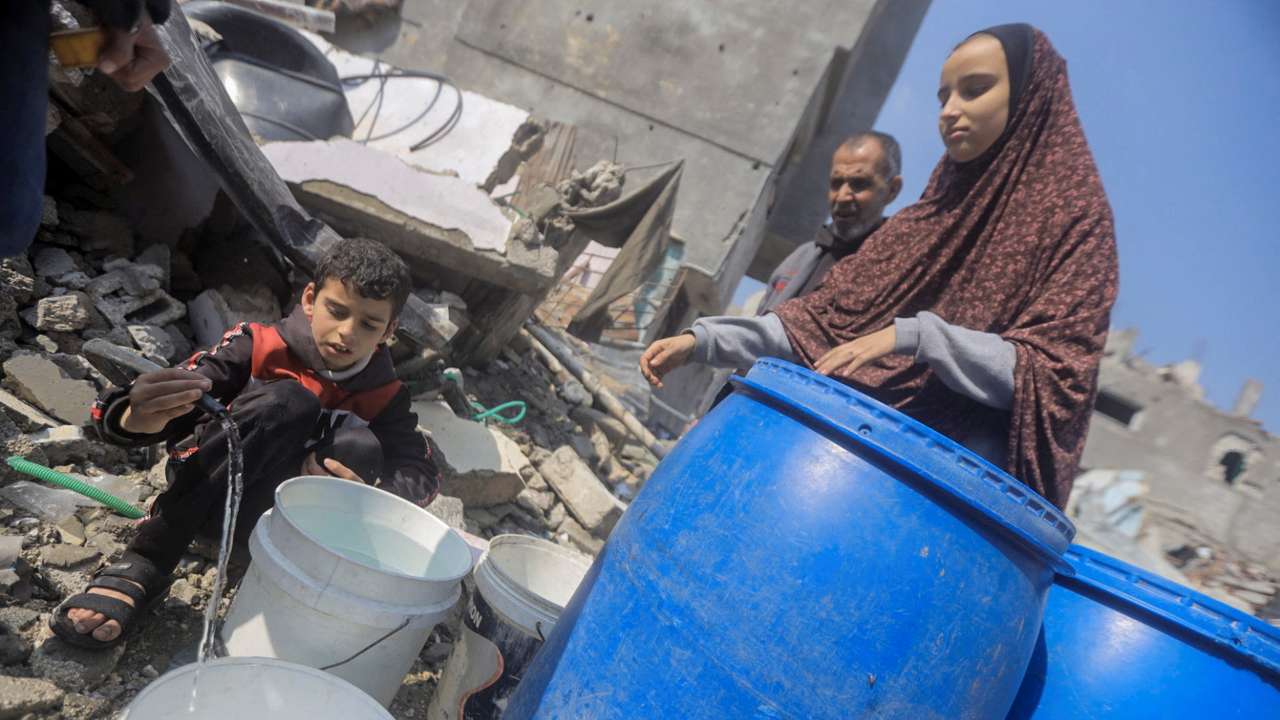 Palestinians collect water from a house destroyed by an Israeli strike, in Jabalia refugee camp in the northern Gaza Strip
