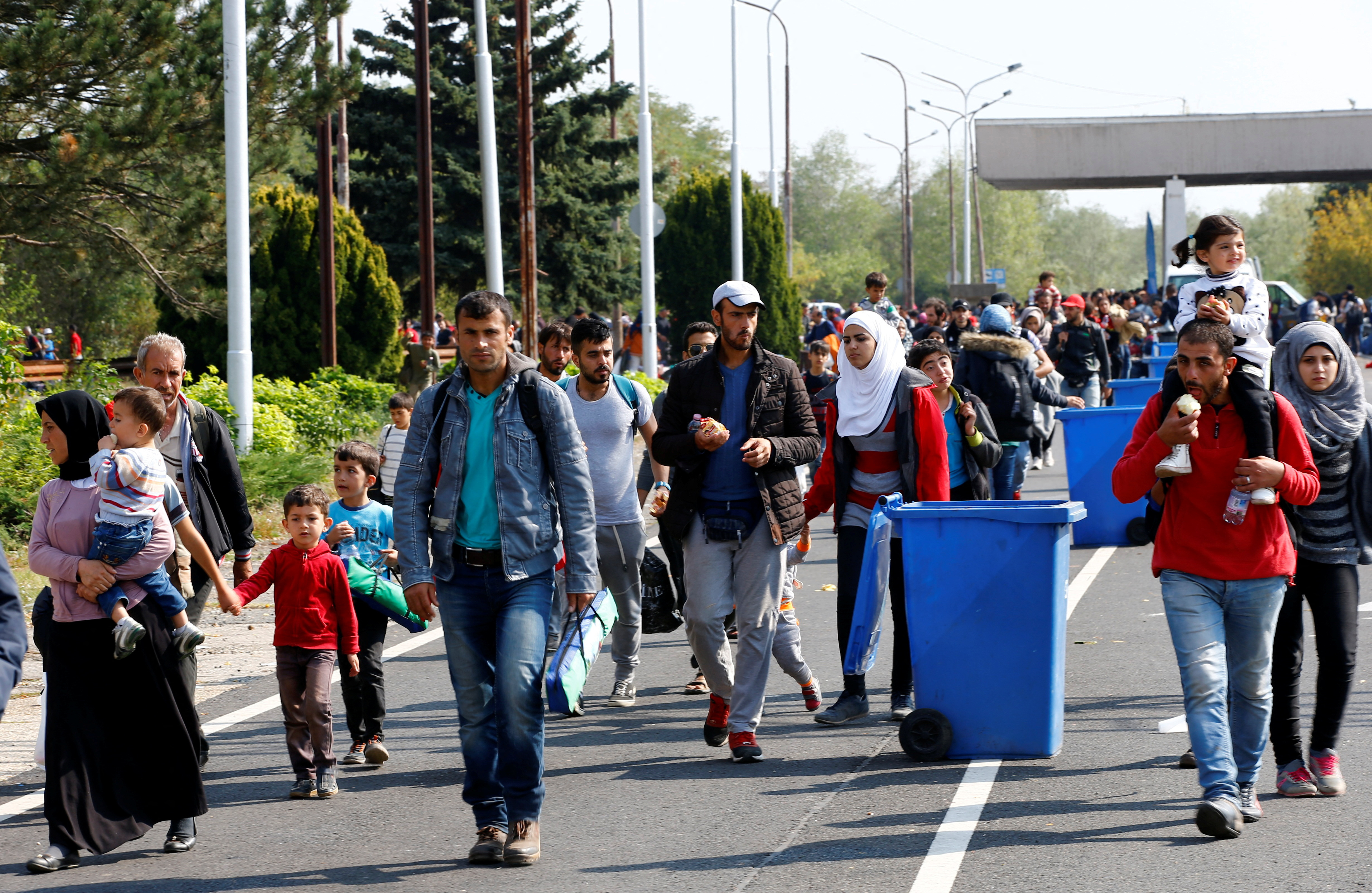 FILE PHOTO: Migrants pass by garbage bins as they walk towards the Austrian border from Hegyeshalom