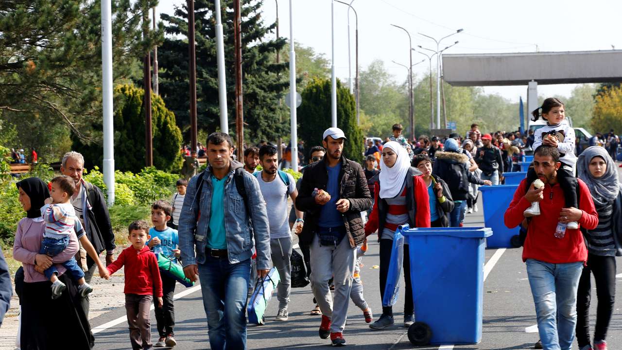 FILE PHOTO: Migrants pass by garbage bins as they walk towards the Austrian border from Hegyeshalom