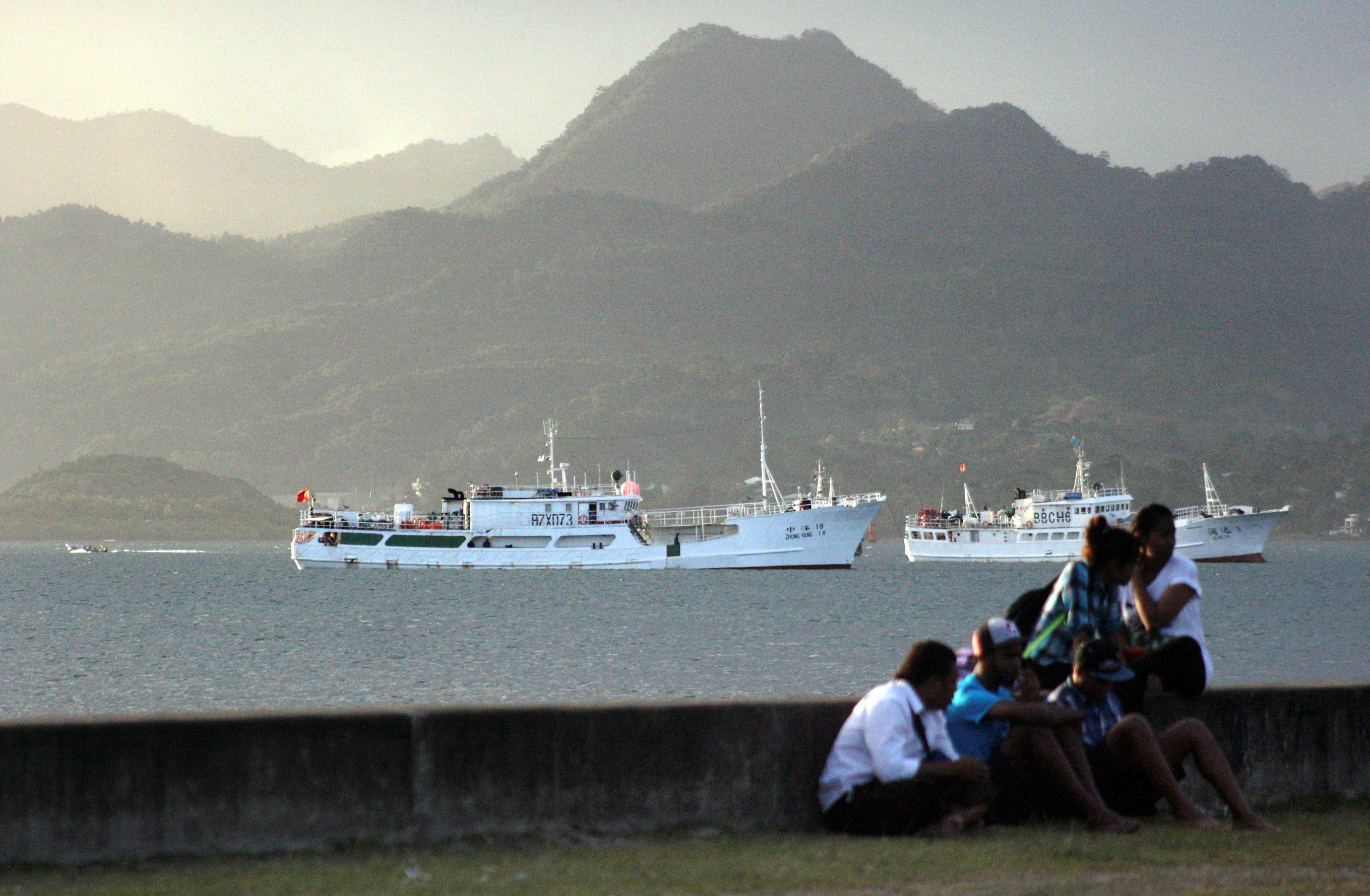FILE PHOTO: Locals sit on a wall situated on the foreshore of the harbour in the Fiji capital of Suva