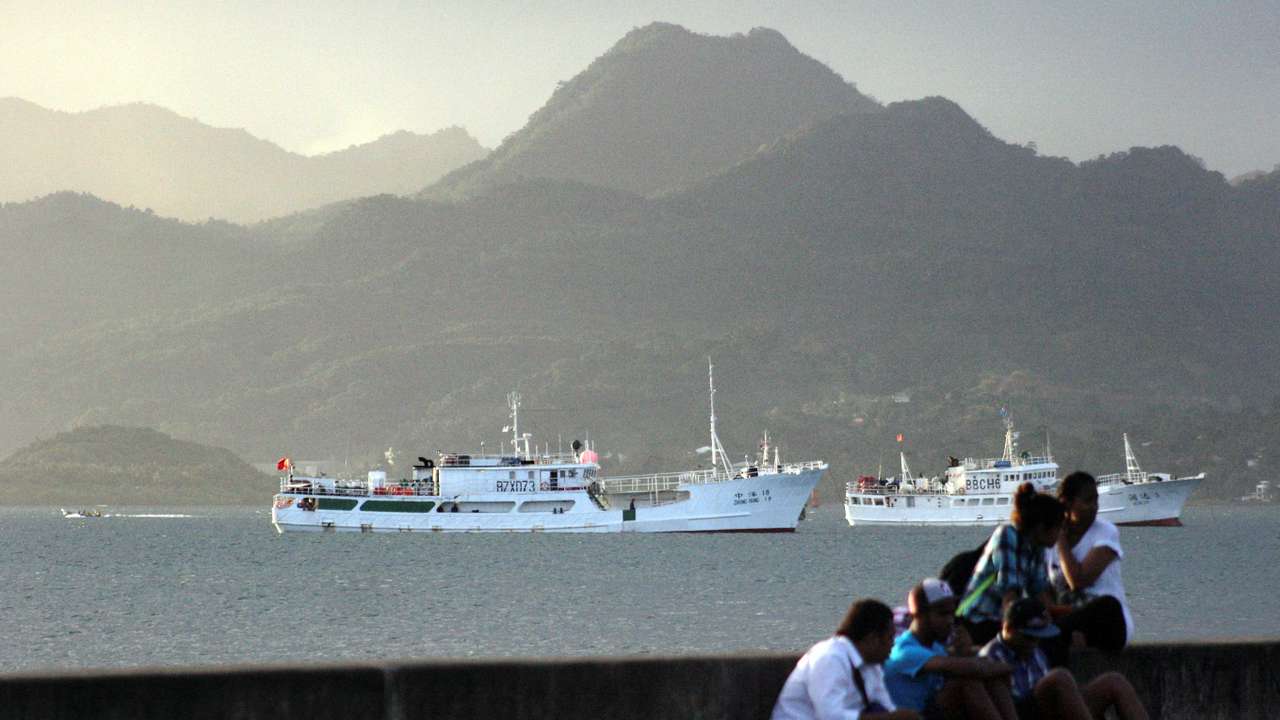 FILE PHOTO: Locals sit on a wall situated on the foreshore of the harbour in the Fiji capital of Suva