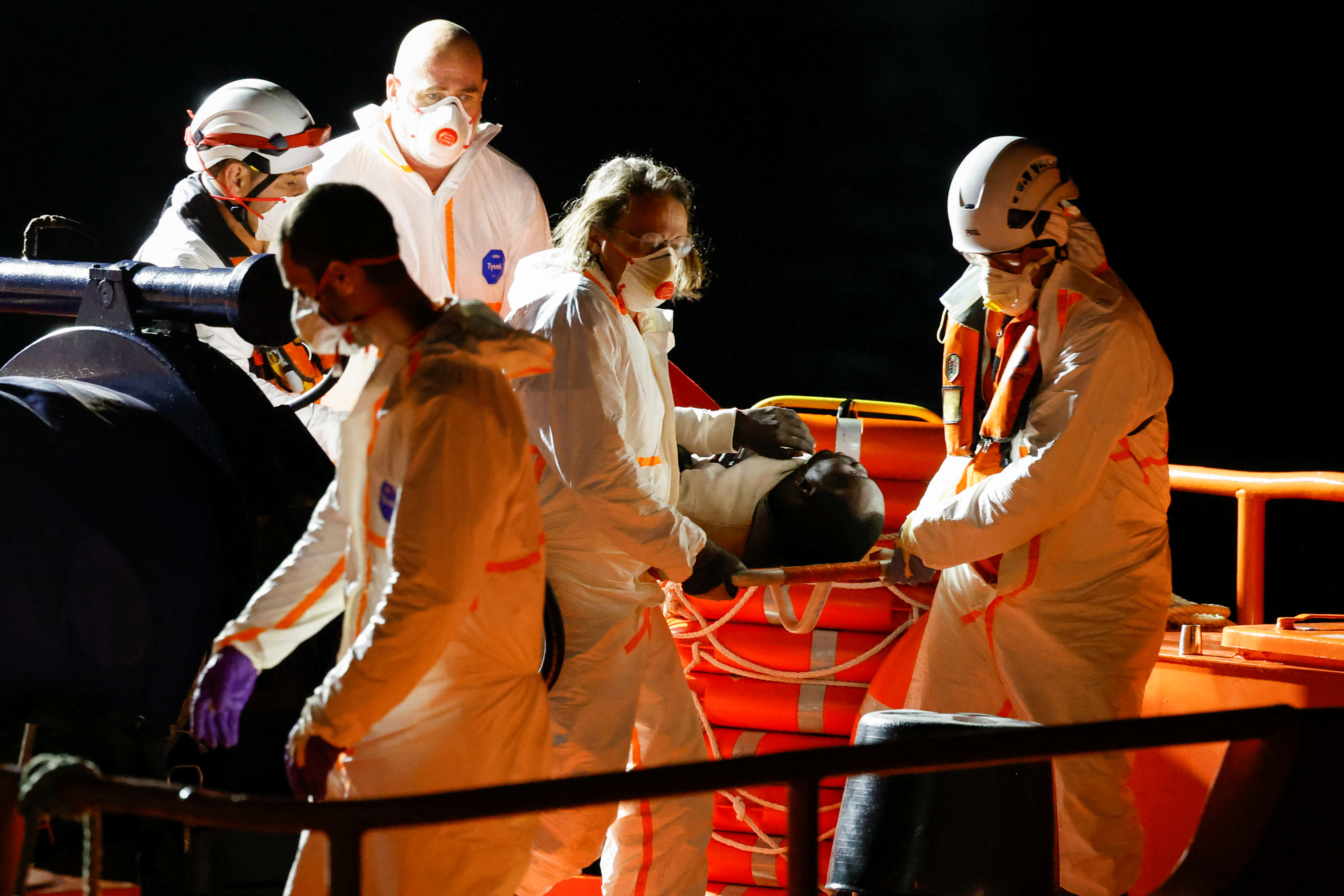 Rescuers disembark a migrant in critical condition from a Spanish coast guard vessel at the port of Arguineguin, on the island of Gran Canaria