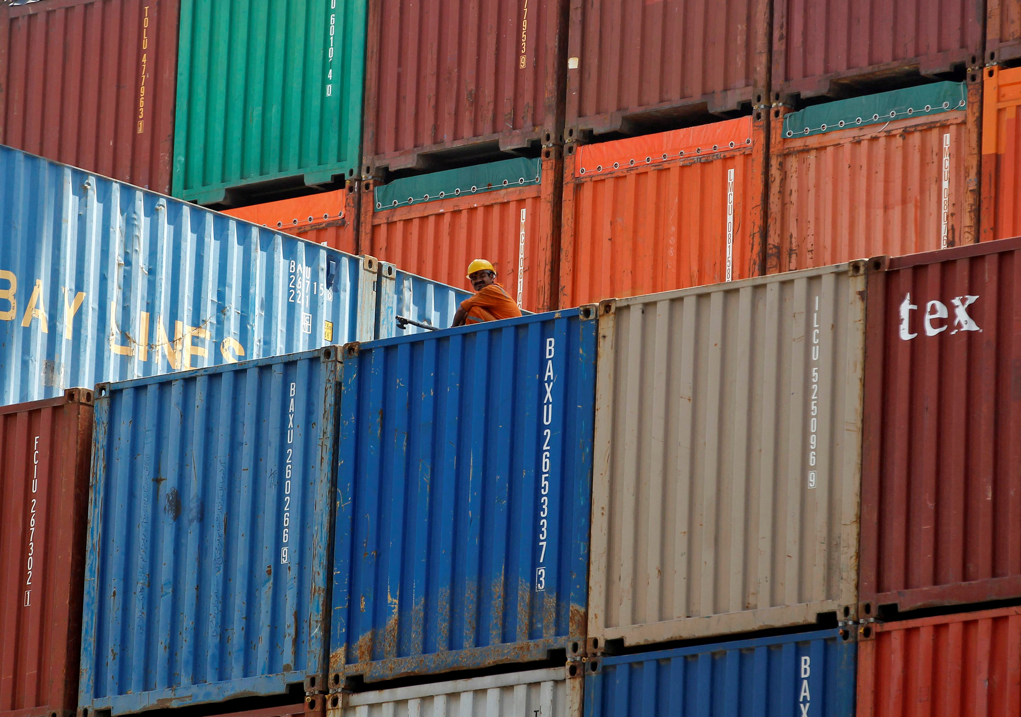 FILE PHOTO: FILE PHOTO - A worker sits on a ship carrying containers at Mundra Port in the western Indian state of Gujarat
