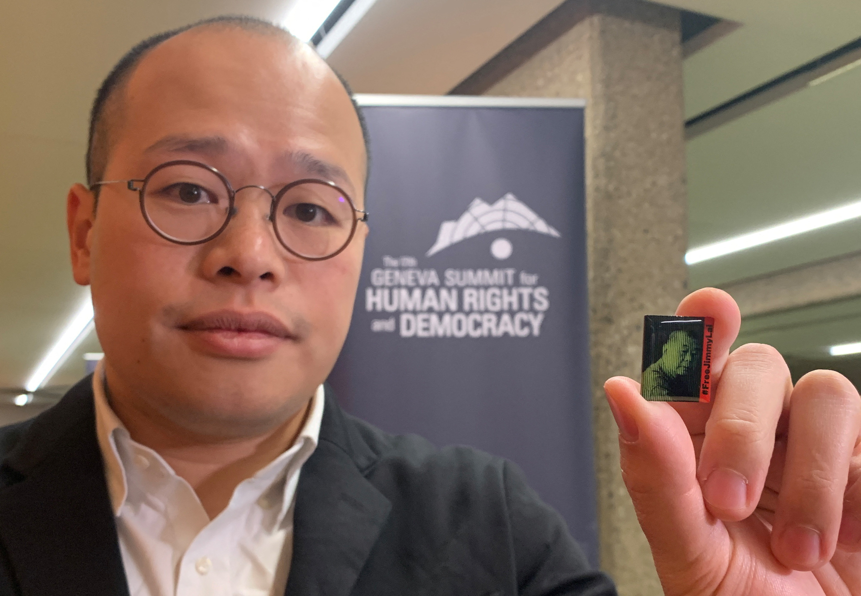 Sebastien Lei, the son of Hong Kong pro-democracy advocate Jimmy Lai, holds a pins with a portrait of his father in Geneva