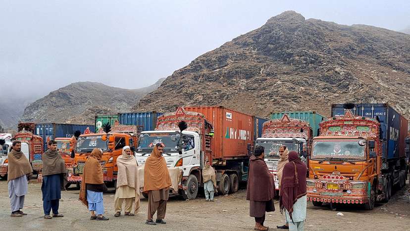 FILE PHOTO: FILE PHOTO: People stand next to parked trucks loaded with supplies at the Torkham border