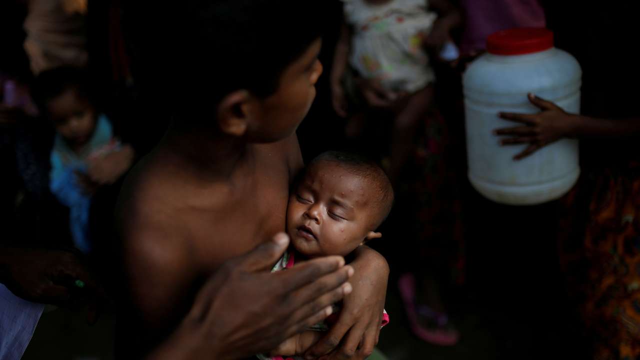 A boy holds a baby as Rohingya refugees wait to receive food supplies at a World Food Programme distribution at the Balukhali refugee camp near Cox's Bazar