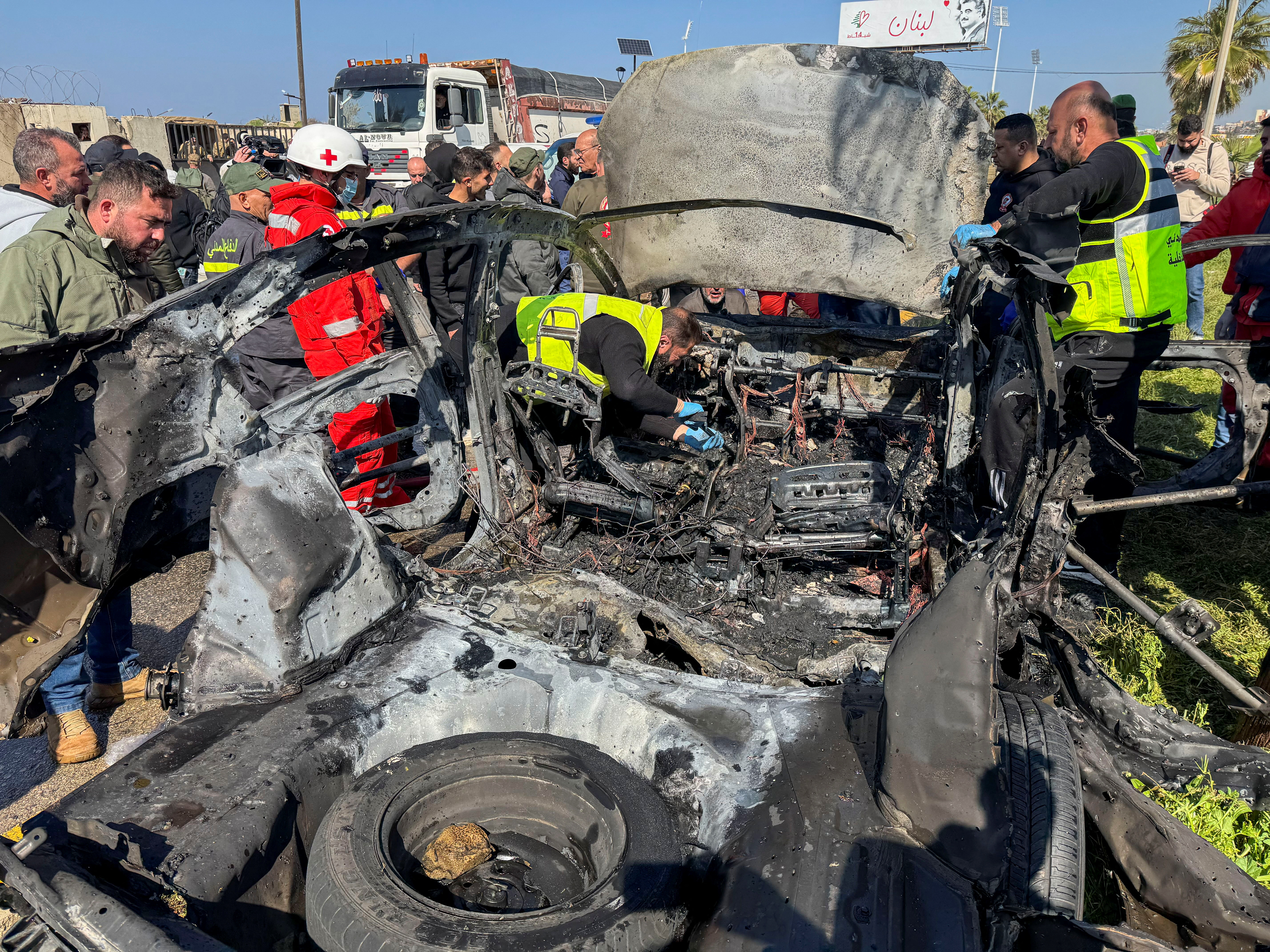 Members of civil defence inspect a damaged car after an Israeli strike, according to security sources, at the southern port city of Sidon