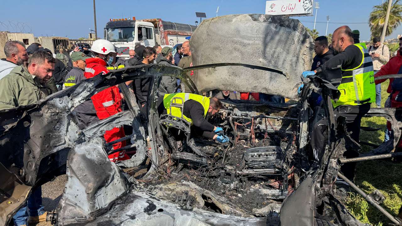 Members of civil defence inspect a damaged car after an Israeli strike, according to security sources, at the southern port city of Sidon