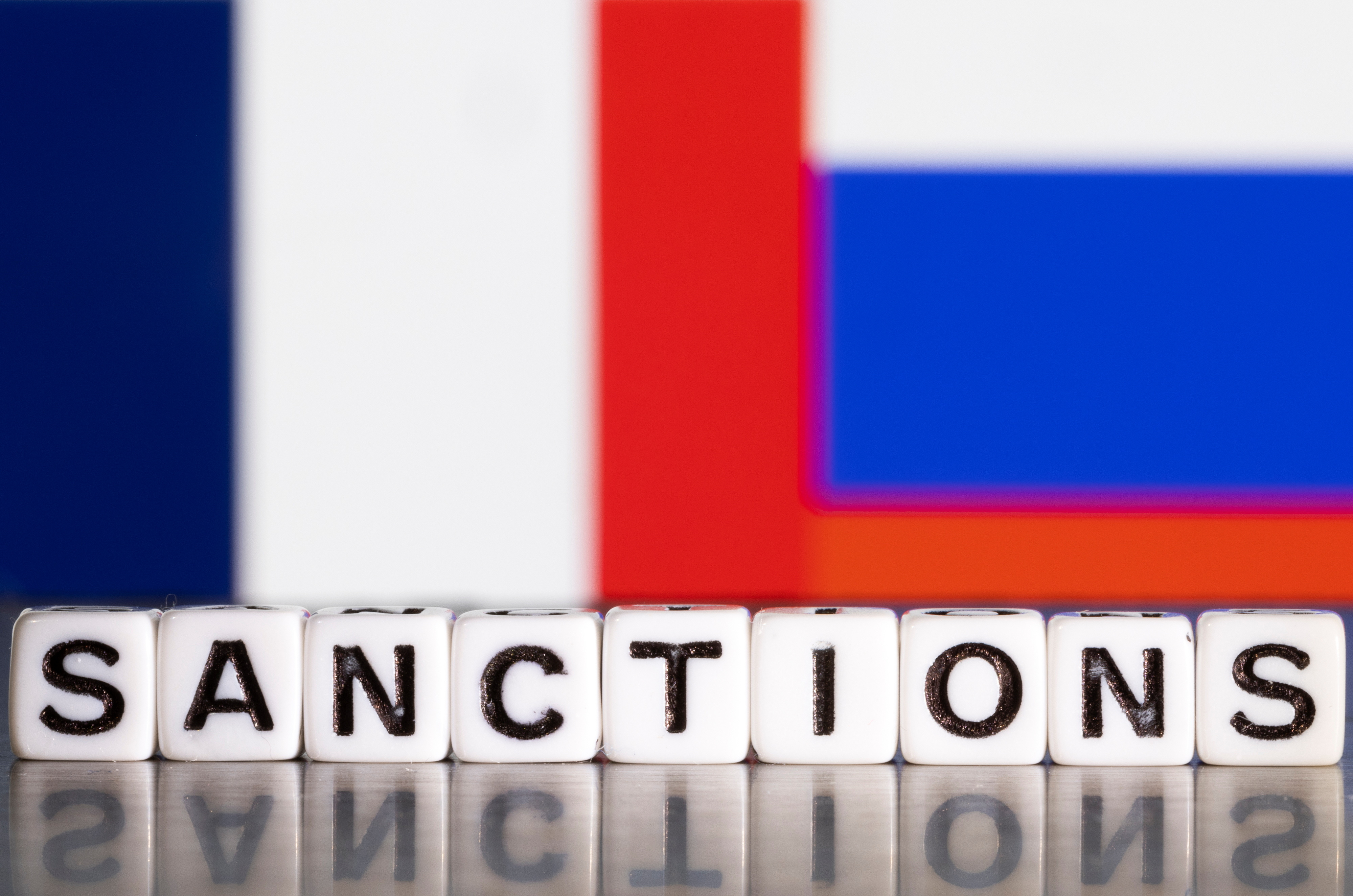Illustration shows letters arranged to read "Sanctions" in front of flag colors of France and Russia