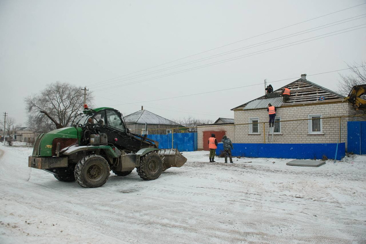 Workers repair the roof of a damaged house in the village of Petropavlovka
