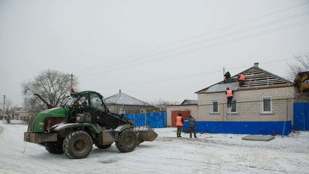 Workers repair the roof of a damaged house in the village of Petropavlovka