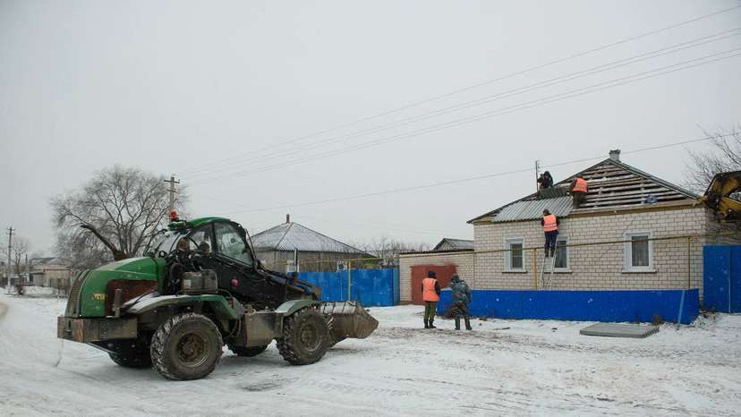 Workers repair the roof of a damaged house in the village of Petropavlovka