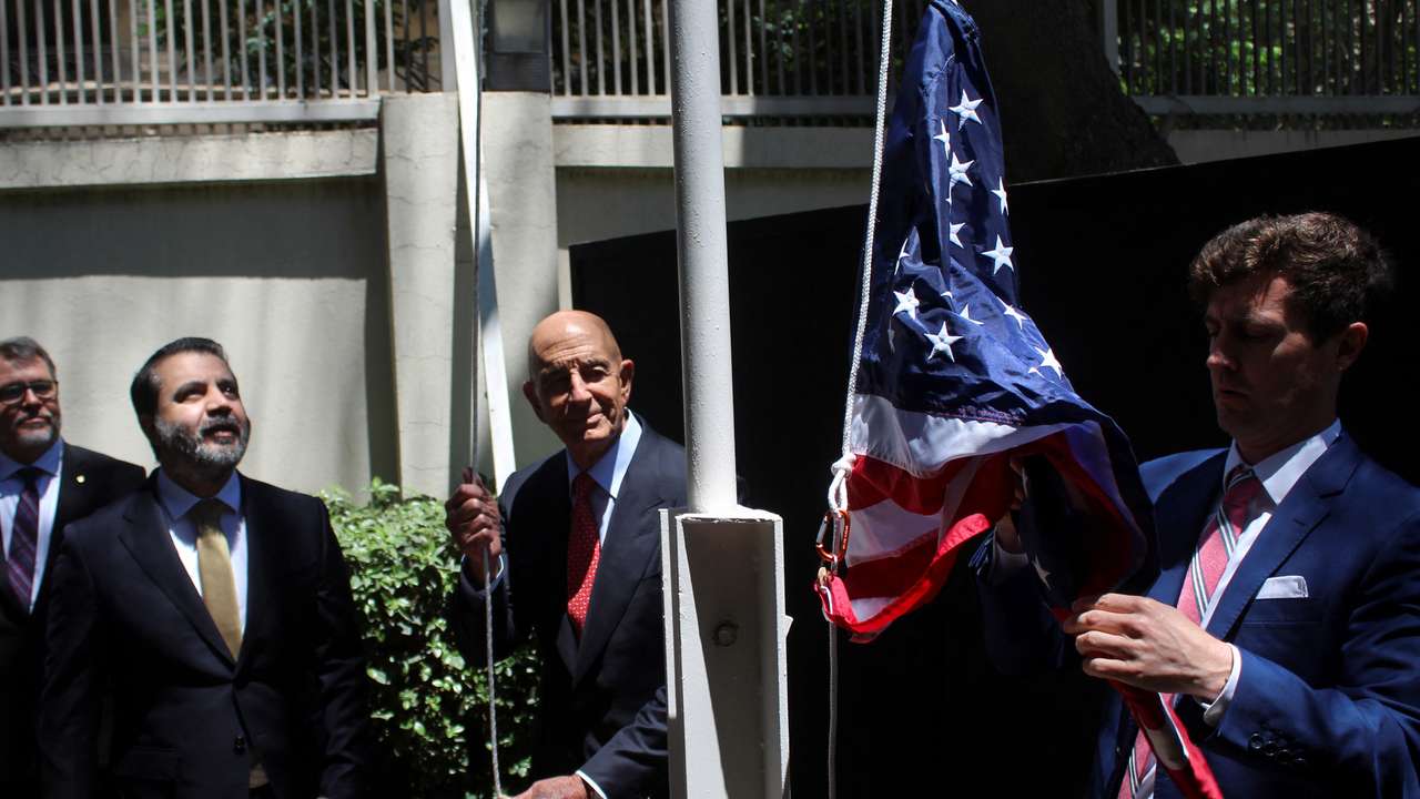 Syrian Foreign Minister Asaad Hassan al-Shibani stands next to U.S. envoy for Syria Thomas Barrack as he raises the American flag at US ambassador's residency in Damascus