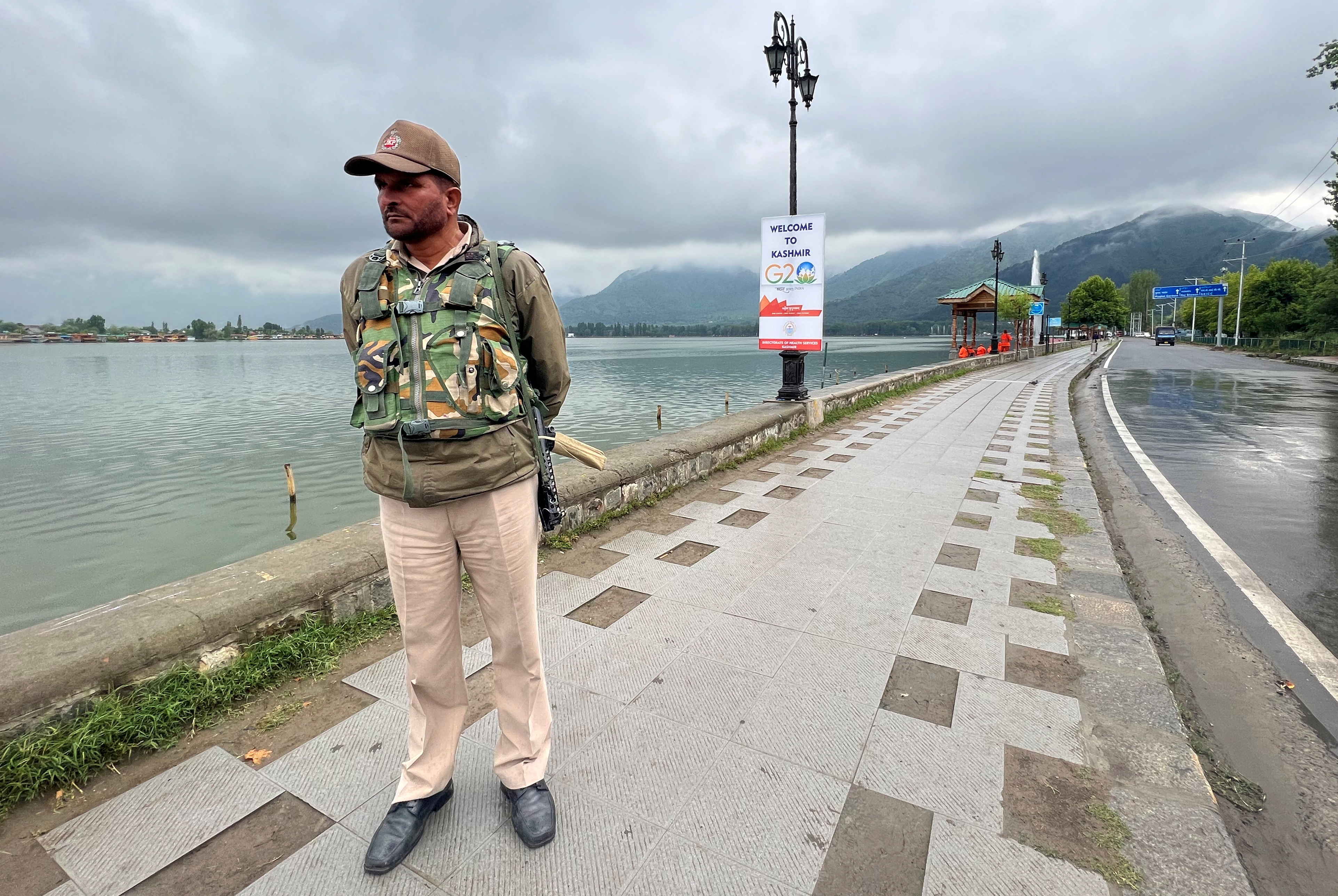 A police officer stands guard along the banks of Dal Lake near the venue of the G20 tourism working group meeting in Srinagar