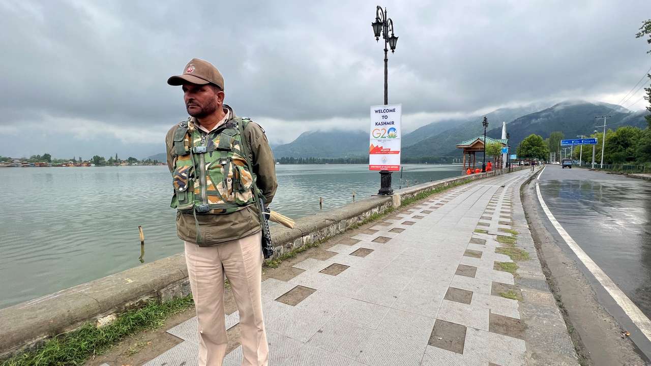 A police officer stands guard along the banks of Dal Lake near the venue of the G20 tourism working group meeting in Srinagar