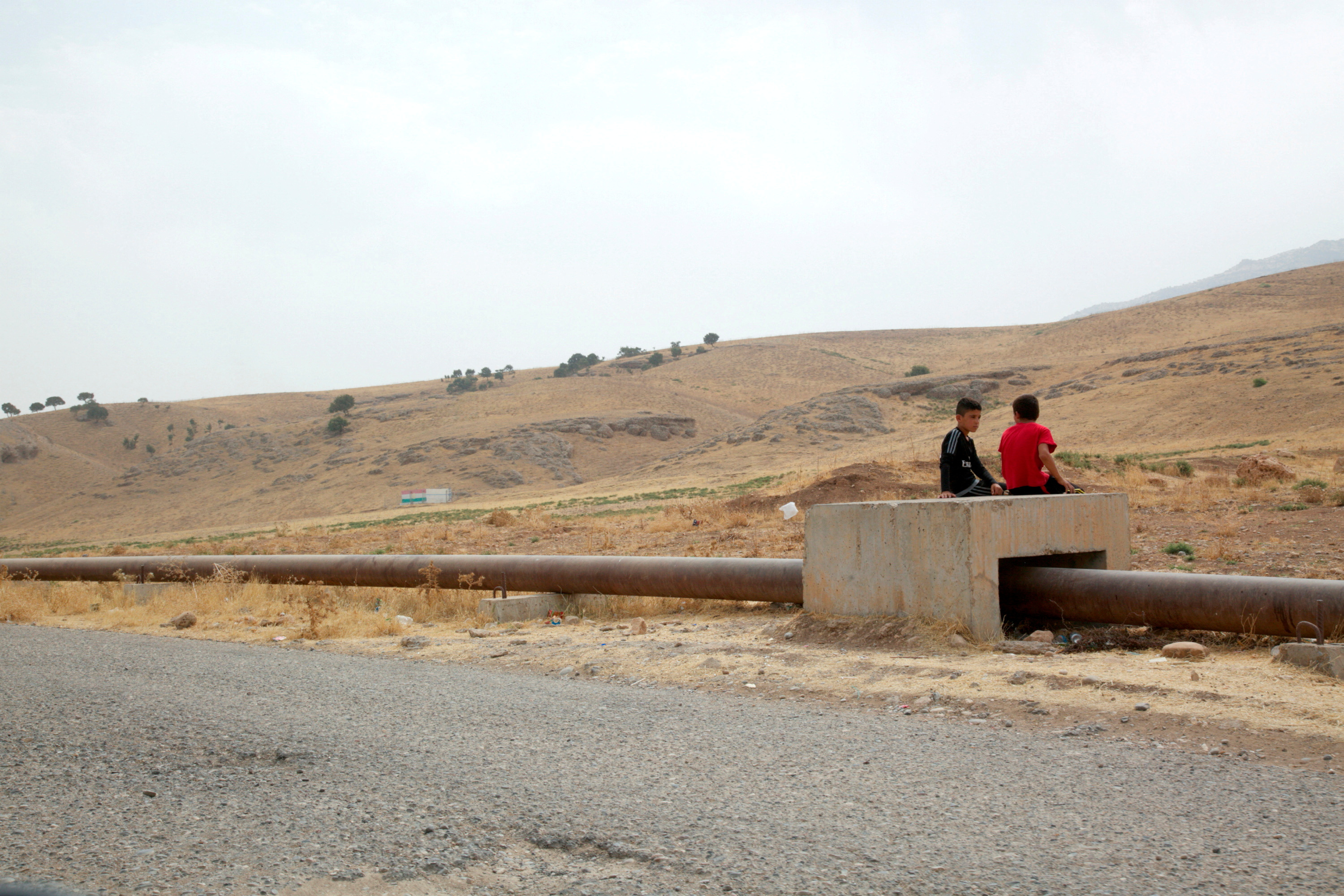 FILE PHOTO: Boys sit on the Iraqi-Turkish pipeline in Zakho district of the Dohuk Governorate of the Iraqi Kurdistan province
