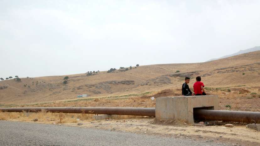 FILE PHOTO: Boys sit on the Iraqi-Turkish pipeline in Zakho district of the Dohuk Governorate of the Iraqi Kurdistan province