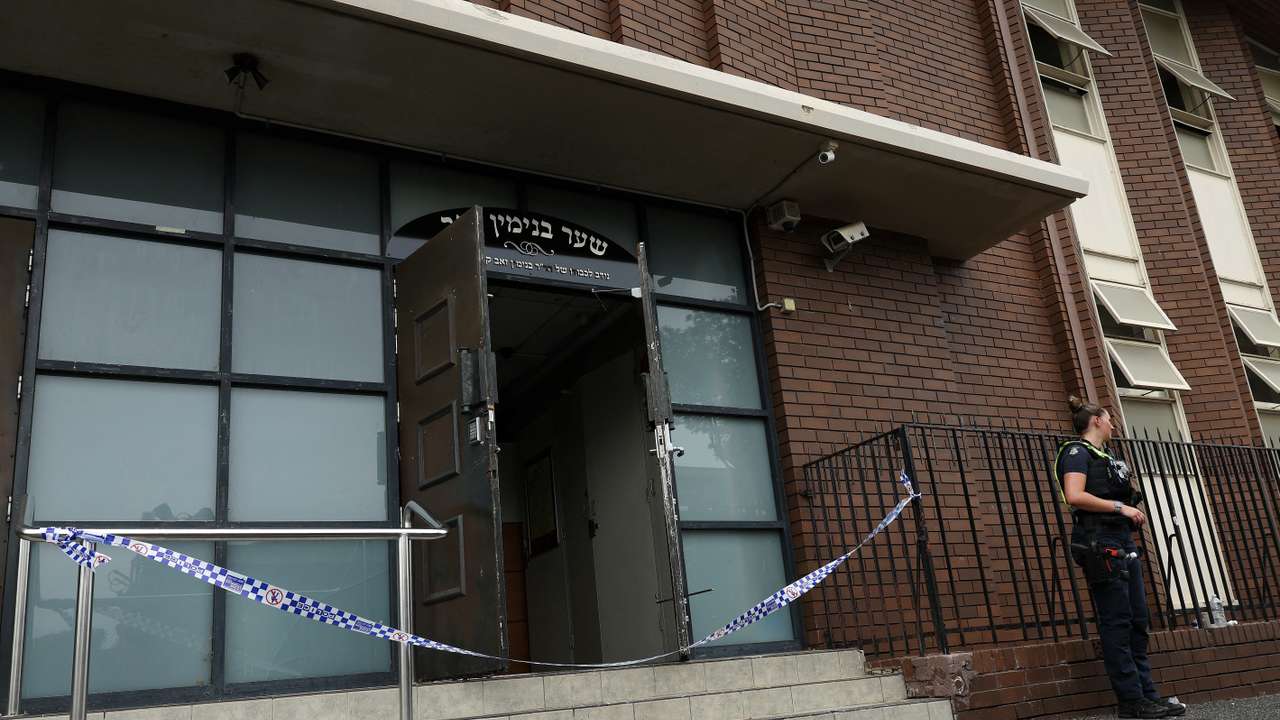 A policewoman stands guard at the scene of a fire at the Adass Israel Synagogue in Ripponlea